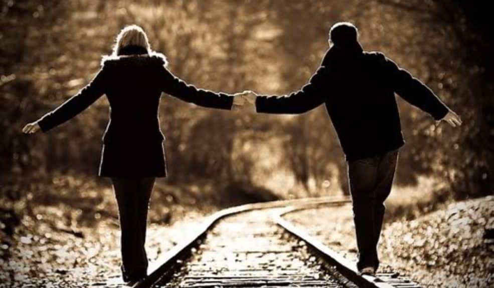 Couple Holding Hands on Train Tracks